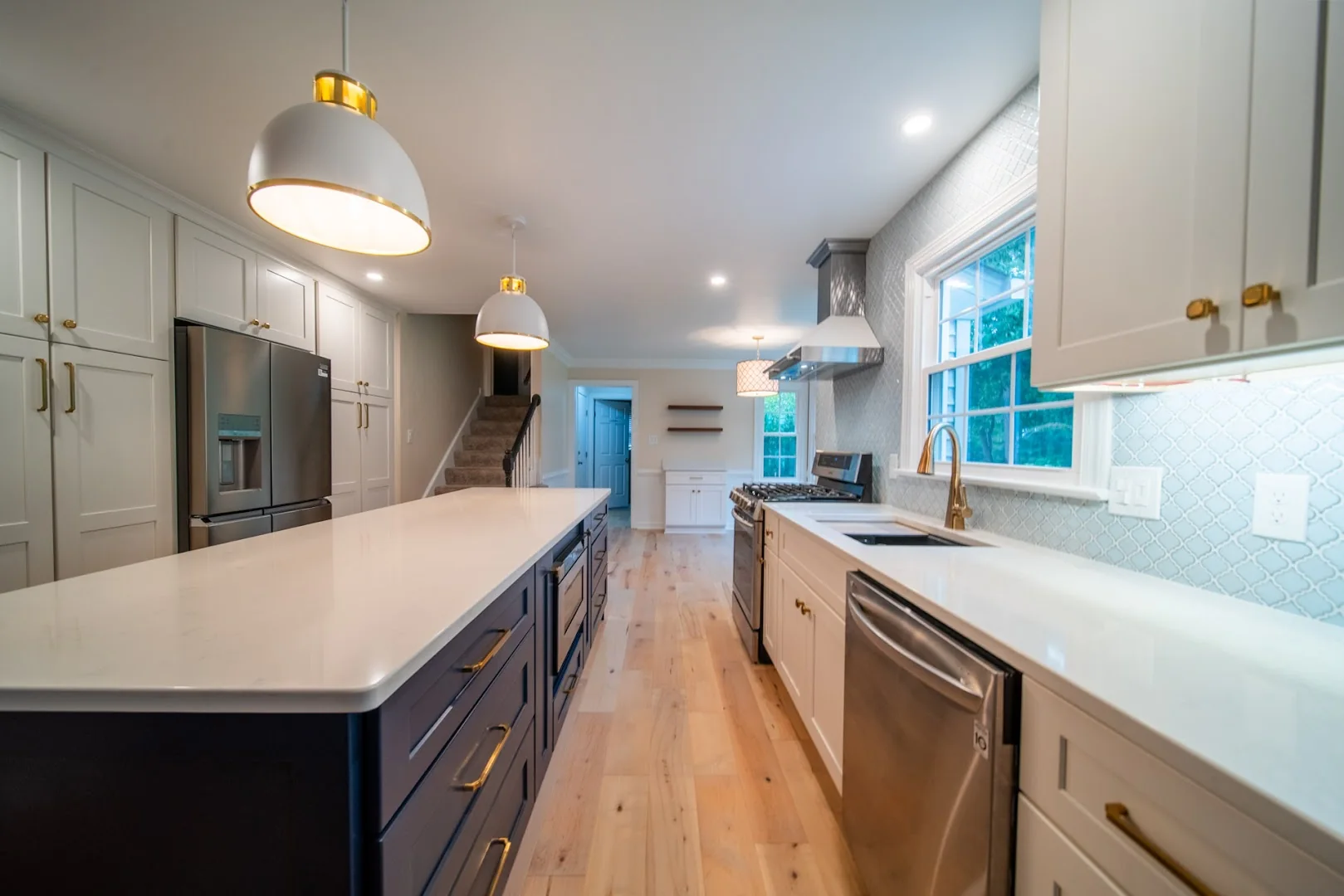 Long kitchen with warm wood floors and a central island